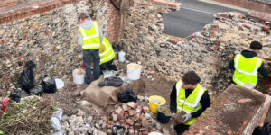Young people working to repair flint walls.