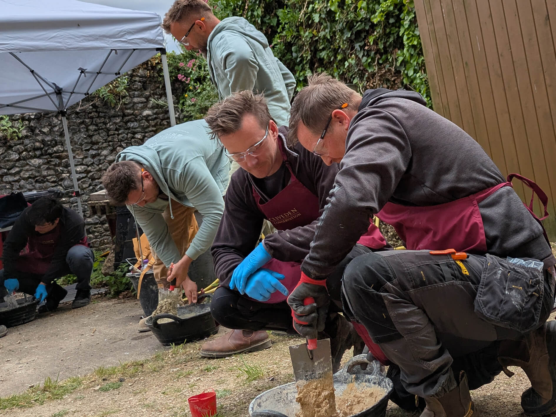 Groups of people mixing lime mortar in buckets