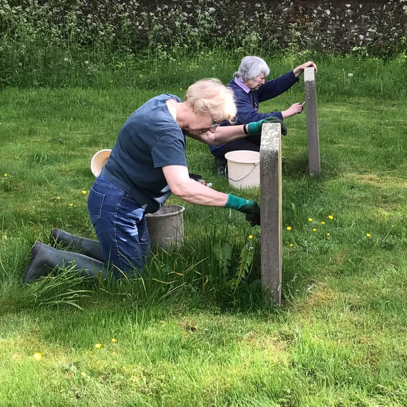 Two ladies cleaning gravestones in a churchyard
